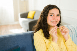 Teen holding clear aligners while learning what can speed up orthodontic treatment in Gurnee IL