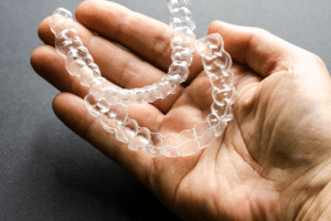 Close-up of a hand holding two clear dental aligners.