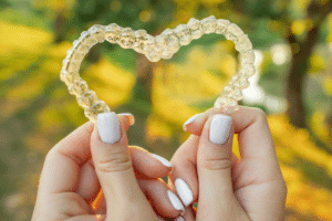 Hands holding a clear orthodontic aligner outdoors